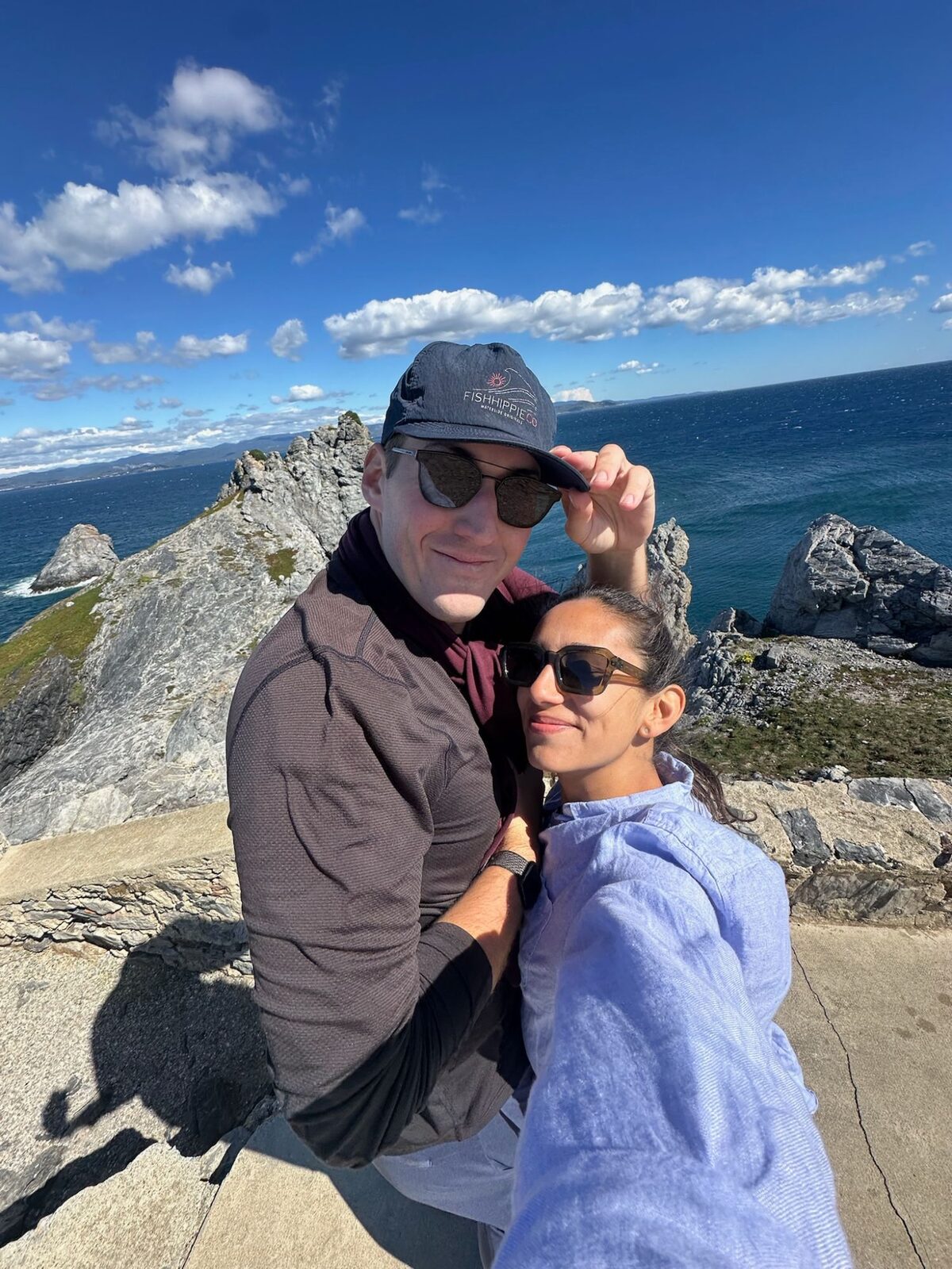 A windy selfie on a rocky point above a deep blue sea