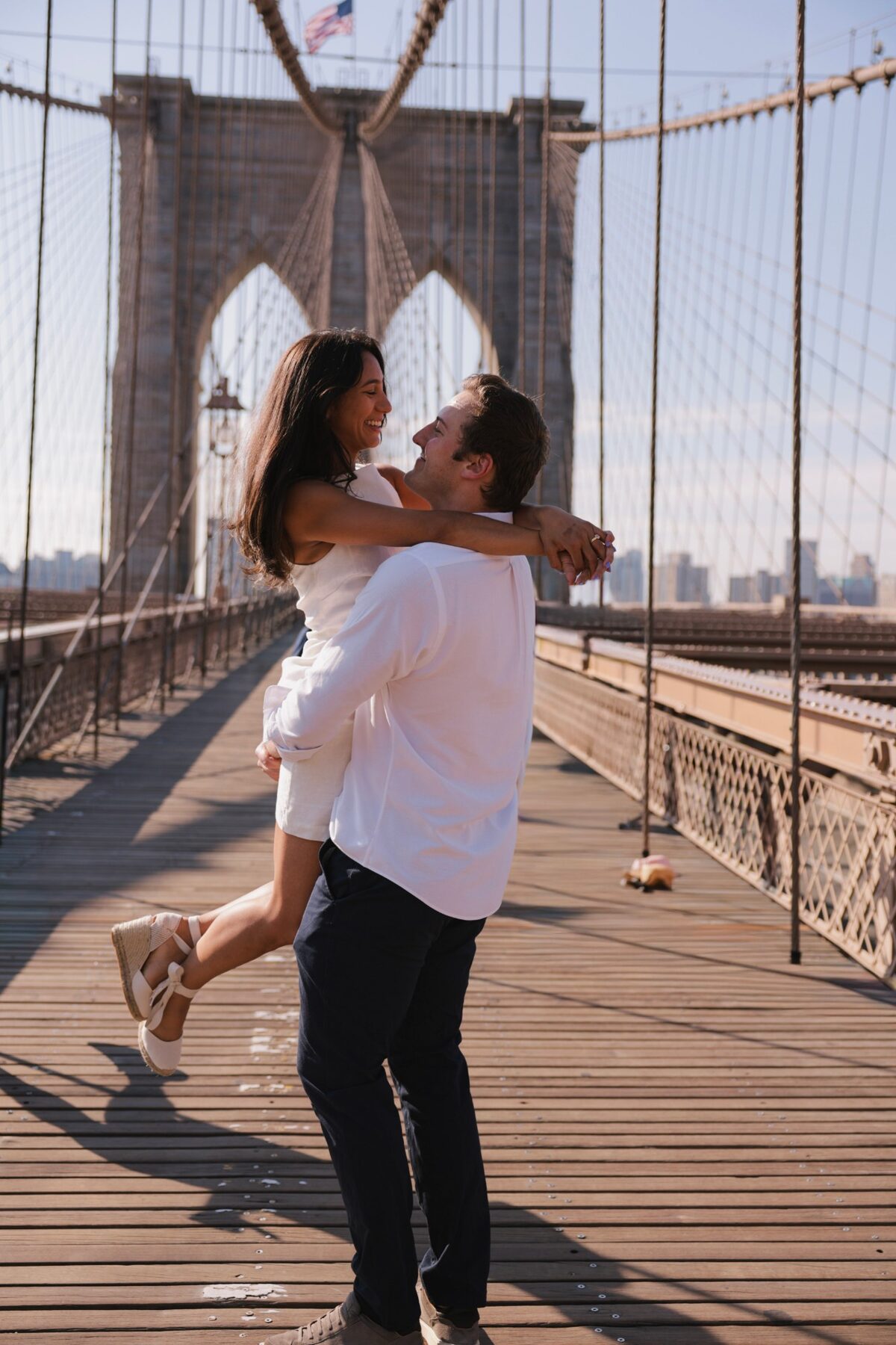 Ryan lifting Maddie on the Brooklyn Bridge walkway, both laughing