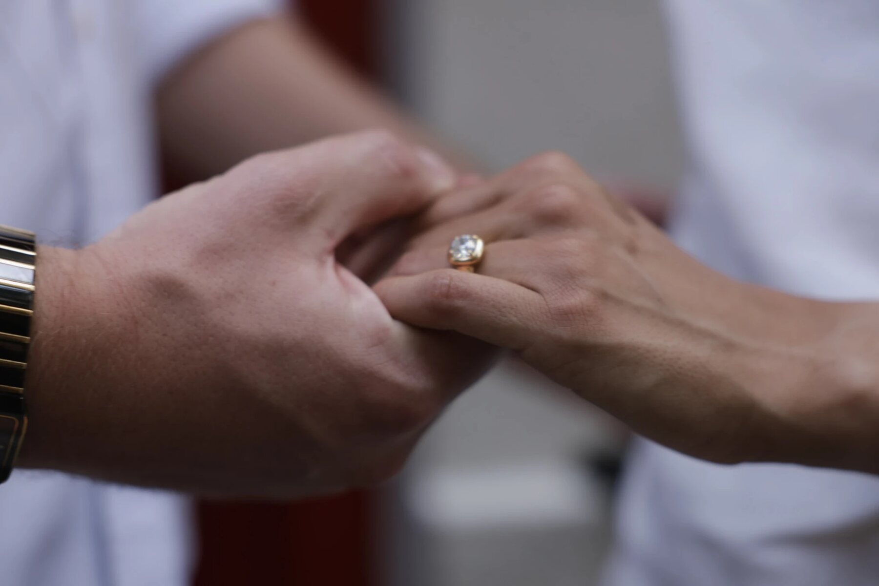 Close-up of Maddie and Ryan holding hands, her engagement ring catching the light