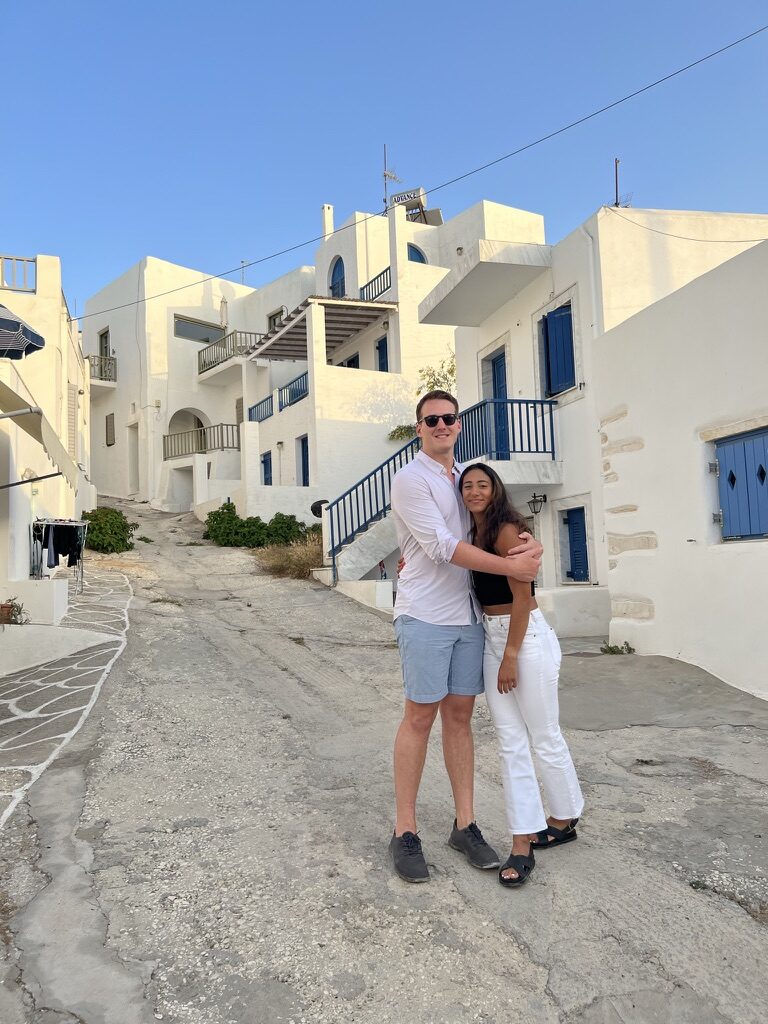 The couple hugging on a whitewashed village lane with blue shutters in Greece